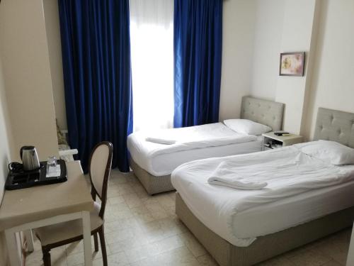 a hotel room with two beds and a table and a desk at Urkmez Hotel in Selcuk