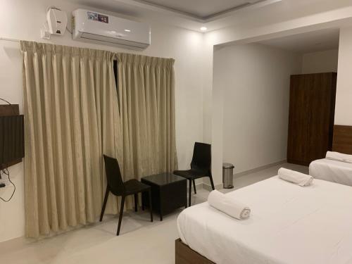 a hotel room with a bed and a desk and chairs at JN Guestline in Devanahalli-Bangalore
