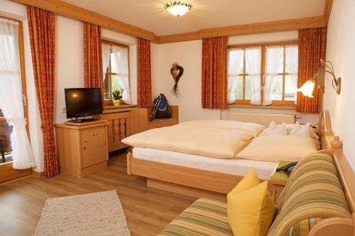 a bedroom with two beds and a tv and a couch at Haus am Schmiedweg in Reit im Winkl