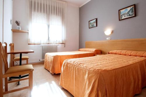 - une chambre avec 2 lits, une table et une fenêtre dans l'établissement Hostal Montserrat, à Tona
