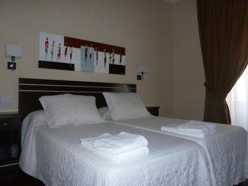 a hotel room with a white bedspread and a white comforter at Hostal Mayor in Madrid