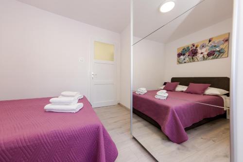 1 dormitorio con cama morada y espejo en Apartman Ankica, en Kaštela