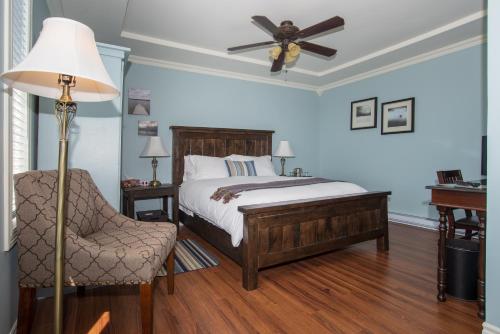 a bedroom with a bed with a ceiling fan and a chair at The Bayside Bed and Breakfast in Bareneed