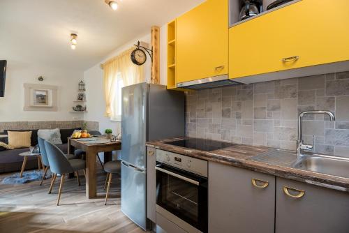 a kitchen with yellow cabinets and a dining room at Apartment Cesarica in Baška Voda