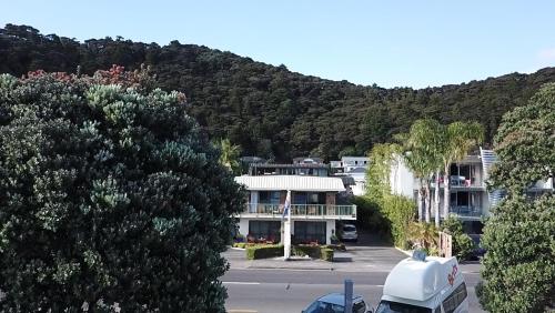 a building in a parking lot with a mountain at Bay Sands Seafront Studios in Paihia
