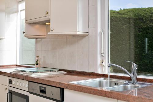 a kitchen with a sink and a window at Alexanderpark 5 - Ouddorp, covered terrace, near to the beach and dunes - not for companies in Ouddorp