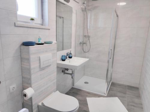 bagno bianco con doccia e lavandino di Maristo Apartments a Stara Novalja