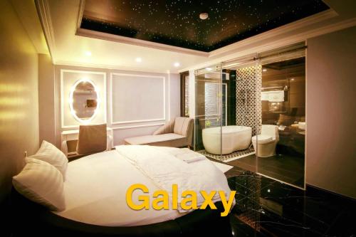a bedroom with a white bed and a bathroom at La Galerie Hotel in Ho Chi Minh City