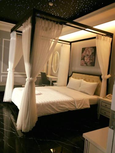 a bedroom with a canopy bed with white curtains at La Galerie Hotel in Ho Chi Minh City