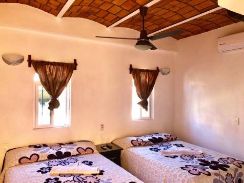 two beds in a room with two windows at Bungalows Princeza Guayabitos in Rincon de Guayabitos