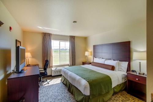 ClintonvilleにあるCobblestone Inn & Suites - Clintonvilleのベッド、デスク、テレビが備わるホテルルームです。