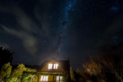 a house lit up at night with a starry sky at The Last Straw Cottage Nelson in Brightwater