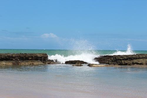 a wave crashing on the rocks in the ocean at Pontal dos Sonhos- Chalés Praia do Farol in Coruripe