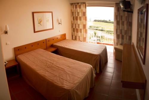 a hotel room with two beds and a window at Areia Dourada in Porto Santo
