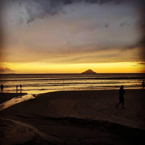 a group of people walking on the beach at sunset at Mares de Camburizinho in Camburi