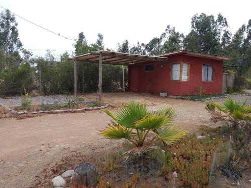 una pequeña casa roja en un patio con árboles en Cabañita Totoverde, en El Totoral