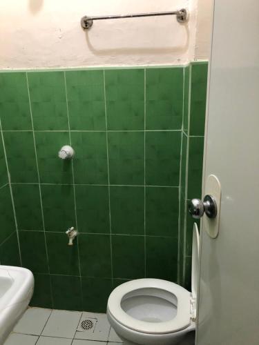 a green tiled bathroom with a toilet and a sink at Edem Tourist Inn Malapascua in Malapascua Island