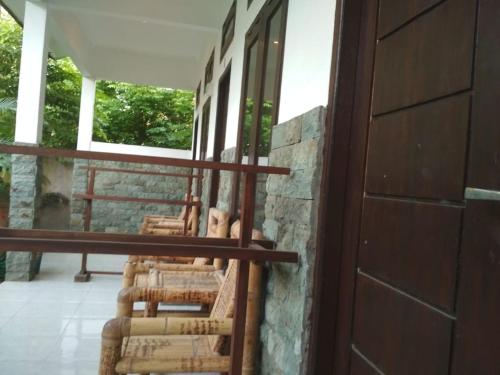 a row of chairs sitting on a porch next to a door at ALMAIDA II Gili Trawangan in Gili Trawangan
