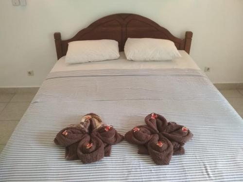 a bed with two brown knitted shoes on it at ALMAIDA II Gili Trawangan in Gili Trawangan