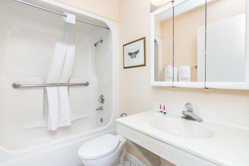 Baño blanco con aseo y lavamanos en Days Inn & Suites by Wyndham Lake Okeechobee, en Okeechobee