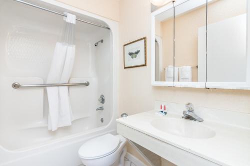 une salle de bain blanche avec toilettes et lavabo dans l'établissement Days Inn & Suites by Wyndham Lake Okeechobee, à Okeechobee