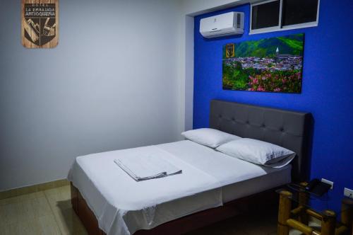 a bedroom with a bed with a blue wall at Hotel la Embajada Antioqueña in Cúcuta
