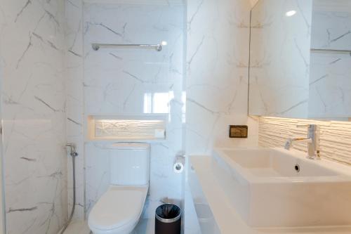a white bathroom with a toilet and a sink at Seaside Jomtien Beach Pattaya in Jomtien Beach