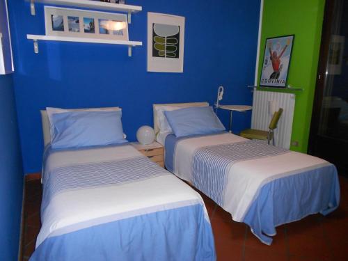 - 2 lits dans une chambre aux murs bleus et verts dans l'établissement B&B Come A Casa, à Cerrione