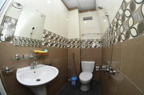 W łazience znajduje się umywalka, toaleta i lustro. w obiekcie Nhà nghỉ Hùng Hoa w mieście Phan Thiet