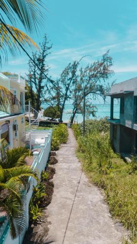 a walking path next to a house and the ocean at Villa Bella Charming Beachfront Guesthouse in Blue Bay