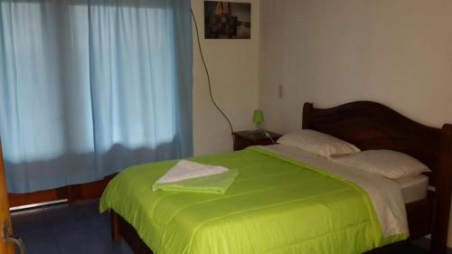 a bedroom with a green bed with a window at Cabinas Lindo Horizonte in San Pedro