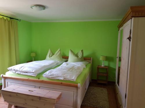 een groene slaapkamer met een bed met witte lakens en kussens bij Hering FeWo I Apartment Terrace in Wiek auf Rügen 