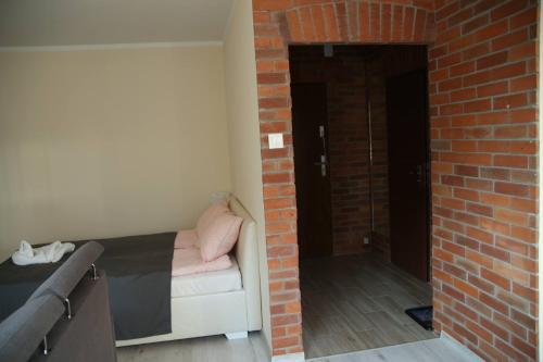 Cette chambre dispose d'un lit et d'un mur en briques. dans l'établissement ALIBI Apartament Boleslawiec, à Bolesławiec