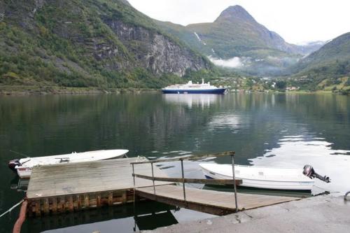 two boats are docked at a dock on a lake at Solhaug Fjordcamping in Geiranger