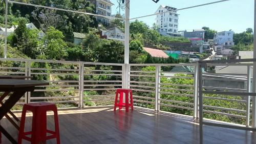 two red chairs sitting on a balcony with a view at MrLee Dalat House in Da Lat