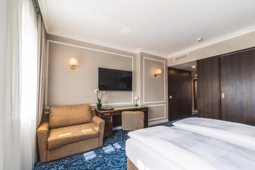 a hotel room with a bed and a chair and a desk at Hotel Suitess in Dresden