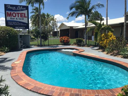 a swimming pool with a brick walkway around it at True Blue Motor Inn in Rockhampton