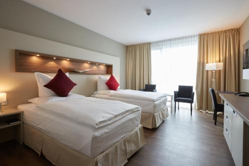 a hotel room with two beds and a desk at Privathotel alte mühle Wolfsburg-Weyhausen in Wolfsburg