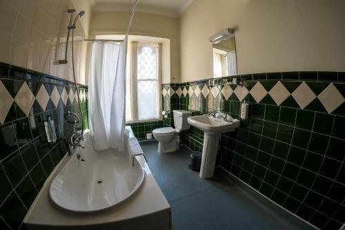a green tiled bathroom with a tub and a sink at Farnley Tower Guesthouse in Durham