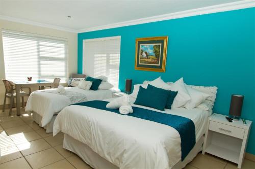 two beds in a room with blue walls at Tranquil Shores in Wilderness