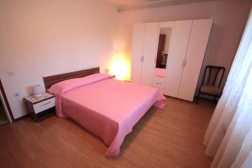 a bedroom with a pink bed and a chair at Sonja-Dajla Apartments in Dajla