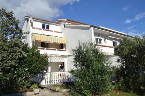 ein weißes Gebäude mit einer Person, die davor steht. in der Unterkunft Apartment Barbat 22 in Barbat na Rabu