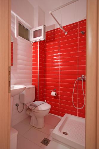 a red bathroom with a toilet and a sink at Mavridis Rooms in Nikiti