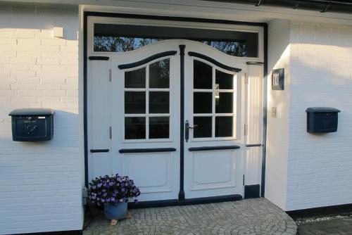 a white door with a window and a vase of flowers at Hummerstübchen Morsum in Morsum
