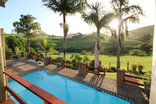 a swimming pool with palm trees and a fence at Farm View Guest House in East London