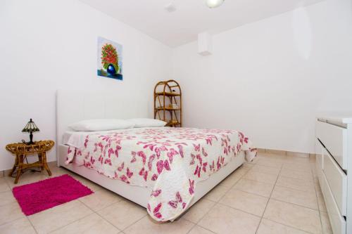 a bedroom with a bed with a pink blanket and a table at Apartments Leon in Podstrana
