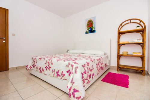 a bedroom with a bed with a pink blanket and a shelf at Apartments Leon in Podstrana
