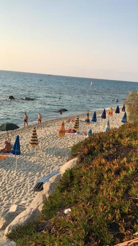 a beach with umbrellas and people in the water at Villa Grazia in Capo Vaticano