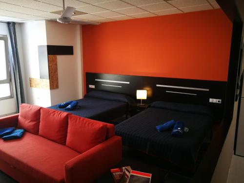 a room with two beds and a red couch at 1V - LUXURY APARTMENT NEAR BEACH in Puerto del Rosario