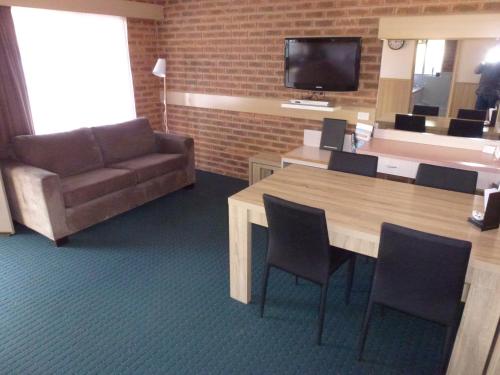 a living room with a couch and a table with chairs at Colonial Motor Inn Bairnsdale Golden Chain Property in Bairnsdale